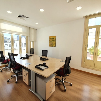 Bright office space for rent at Calle Gran Vía 6, Madrid Center, featuring large windows, desks, and chairs, perfect for office space rental.