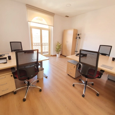 Furnished office space rental on Calle Gran Vía 6 in Madrid Center featuring desks and chairs with sunlight filtering through large windows.