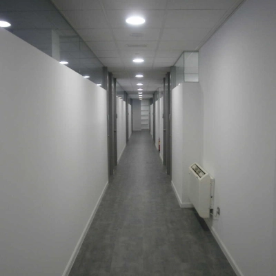 Long corridor in an office building at Plaza Santa María Soledad Torres Acosta 1, in Madrid Center, ideal for office space rental. Bright, with clean lines and modern lighting suitable for professional use.