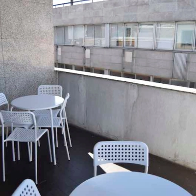 Outdoor office space with white tables and chairs at Plaza Santa María Soledad Torres Acosta 1, ideal for relaxing breaks or meetings.