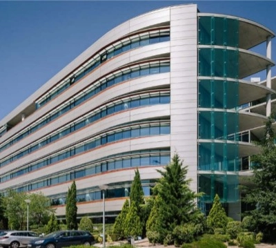 A modern office building at Calle Vía de los Poblados 1, Madrid Hortaleza, ideal for office space rental, surrounded by greenery and parking facilities.