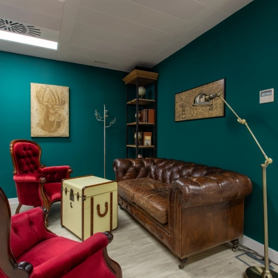 Cozy office space with vintage leather couch, red armchairs, and decor, ideal for office space rental on calle de O'Donnell, Madrid Retiro.