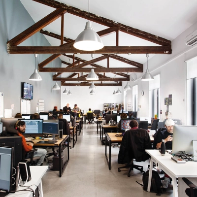 Modern office space in Madrid Retiro at Calle Vandergoten 1 with professionals working at computers under exposed wooden beams, ideal for office space rental.