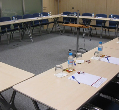 Office space rental at Avenida de Brasil 6, Madrid Tetuán with a conference room setup featuring tables, chairs, and water bottles arranged for a meeting.