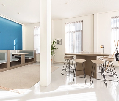 Bright office space at Kardinaal Mercierplein 2 featuring modern furnishings, booths, and a meeting table, ideal for office space rental in Mechelen Centrum.