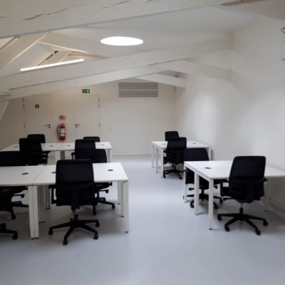 Bright office space available for rent in Mechelen Centrum, featuring black chairs and white desks under modern lighting.
