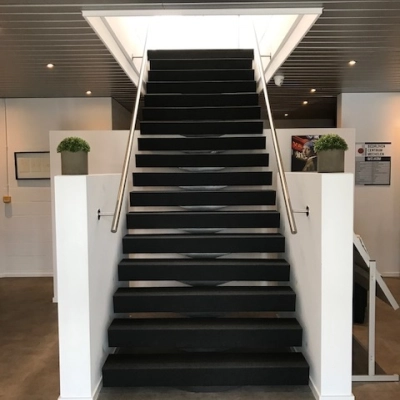Interior view of an office entrance with a central staircase leading upwards. Suitable for office space rental.