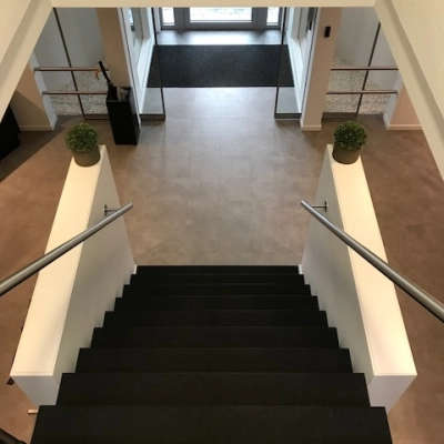 Bright office entrance with modern staircase at De Regenboog 11, ideal for office space rental in Mechelen North.