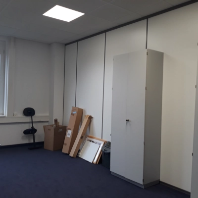 Unfurnished office space for rent on Landsberger Straße, featuring a window, chairs, cabinets, and boxes against carpeted flooring. Ideal for workspaces in München Pasing.