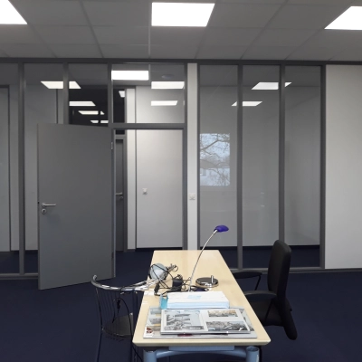 Modern office space at Landsberger Straße 428, München Pasing, featuring a tidy desk setup with chairs against a backdrop of partitioned walls, ideal for office space rental.