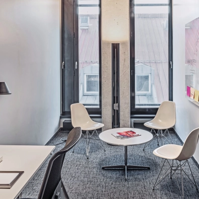 Bright office space for rent at Rosenheimer Straße 143C, München Werksviertel, featuring a meeting area with chairs and a desk with a lamp.