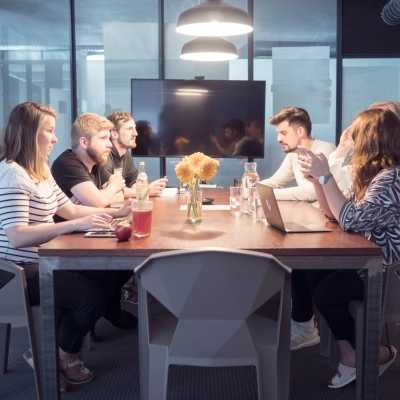 People collaborating in a furnished office space with a large table and modern decor. Ideal for rent office space in Munich Maxvorstadt.