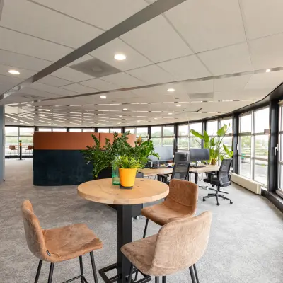Bright, furnished office space at Patroonstraat 13, Nijkerk, ideal for rent. Open floor plan with modern decor and large windows.