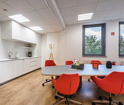 Bright office space at Südwestpark 67, Nürnberg Röthenbach featuring modern furnishings and red chairs around a meeting table, ideal for office space rental.