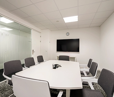 A furnished meeting room in an office to rent at Südwestpark 67, Nürnberg Röthenbach, featuring a long table, chairs, and a TV on the wall.