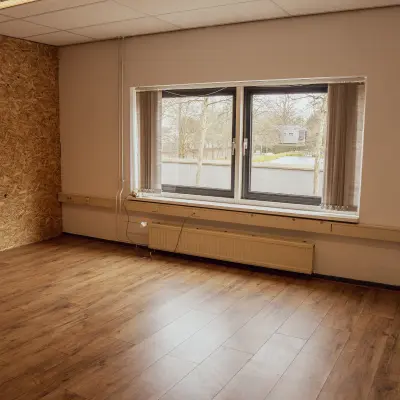 Interior office space at Abdis van Thornstraat 74, Oosterhout Nb, featuring a window overlooking the street and wooden flooring, available for office space rental.