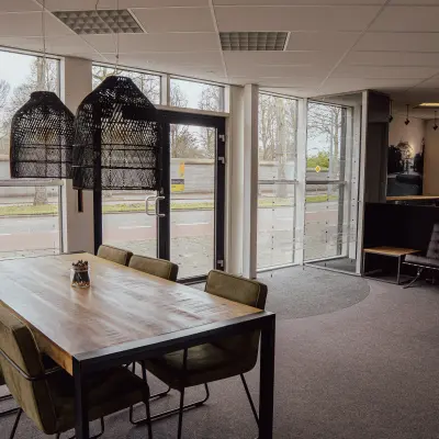 Bright office space with large windows and a wooden table with chairs at Abdis van Thornstraat 74, ideal for office space rental in Oosterhout Nb.