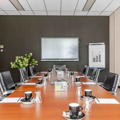 Spacious conference room for office space rental at Leeghwaterstraat 25, featuring a large wooden table and modern black chairs.
