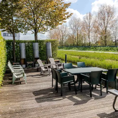 Outdoor patio area with tables and chairs surrounded by greenery, available for rent office space at Leeghwaterstraat 25, Reeuwijk.