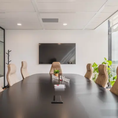 Modern conference room at Laan van Zuid Hoorn 70, Rijswijk, featuring a large table, comfortable chairs, and a sleek TV. Ideal office space rental for meetings.