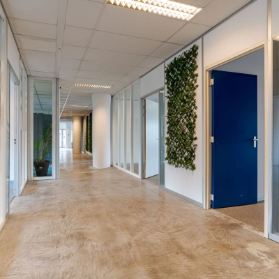 Hallway with wooden floor and glass-walled rooms in an office for rent at Polakweg 7, Rijswijk.