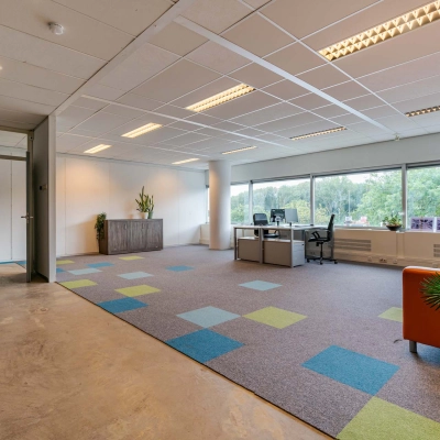 Bright office space at Polakweg 7, Rijswijk, featuring modern furnishings, colorful carpet, and large windows. Ideal choice for office space rental.