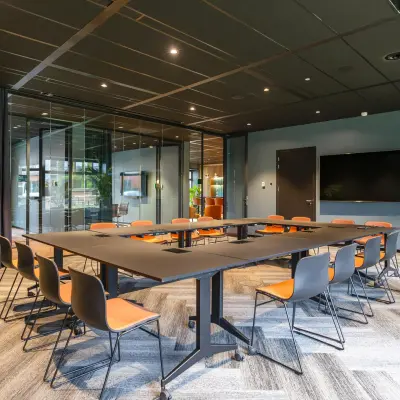 Modern conference room at George Hintzenweg 77 - 89 in Rotterdam Alexander, featuring a large meeting table with chairs and a wall-mounted screen, perfect for office space rental.