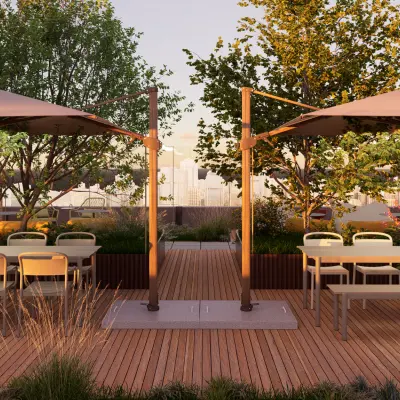 Open rooftop area at Marten Meesweg 101 in Rotterdam Alexander, featuring wooden decking, tables, chairs, and umbrellas, perfect for an office space rental. There are no people visible.