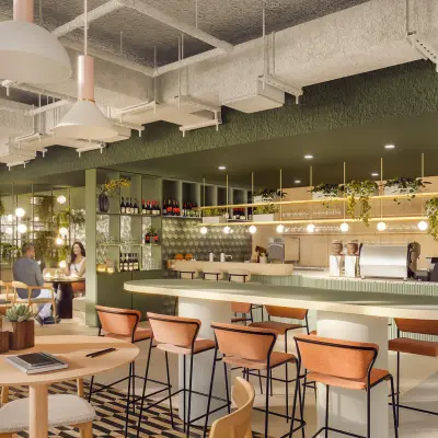 Modern office space with individuals enjoying snacks and drinks at a stylish pantry area in Rotterdam Alexander, ideal for office space rental opportunities.