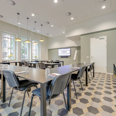 Modern office space rental at Blaak 34, Rotterdam Center, featuring a well-lit conference room with tables, chairs, and a presentation screen.