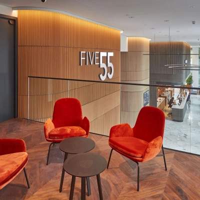 Modern office lounge area at Blaak 555, Rotterdam Center, featuring stylish red chairs and wood paneling. Ideal office space rental opportunity.