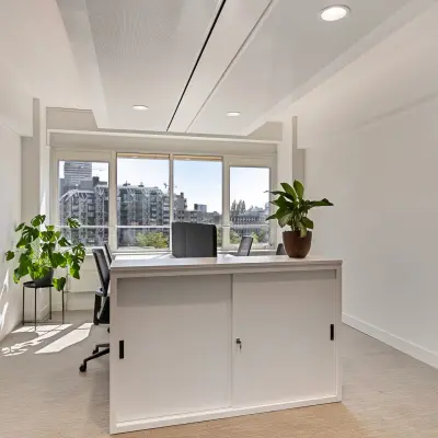 Bright furnished office space rental at Coolsingel 104, Rotterdam Center, with large windows, a few chairs, desks, and plants.