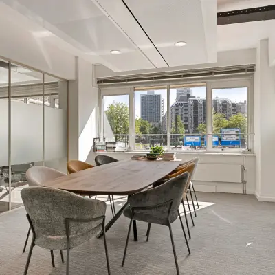 Modern conference room with large wooden table and chairs, offering a bright space for office space rental at Coolsingel 104, Rotterdam Center.