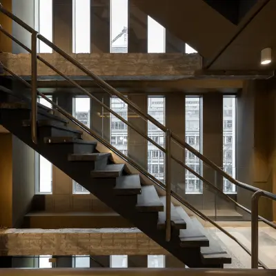 Interior view of a modern office at Stadhuisplein 9-23, Rotterdam Center, featuring industrial-style staircases and windowed walls. Ideal for office space rental.