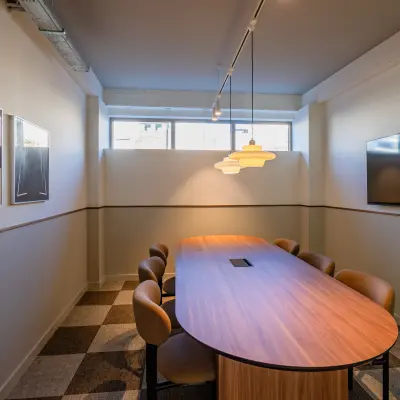 Rent office space in Rotterdam Center with a well-lit conference room featuring a wooden table, cushioned chairs, and a wall-mounted TV at Stadhuisplein 9-23.
