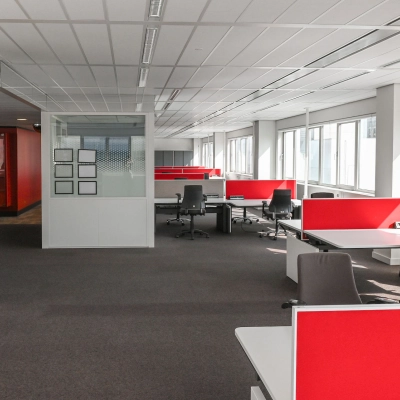 Bright office space rental at Weena 70, Rotterdam Center, featuring modern workstations with red dividers and ample natural light, ideal for businesses seeking an office to rent.