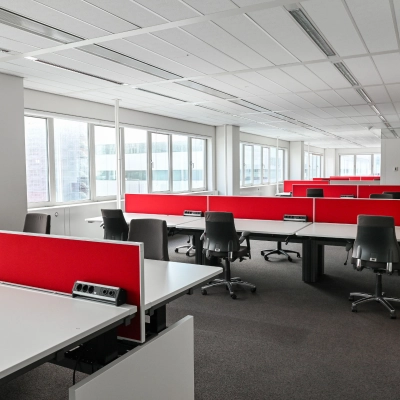 Bright office space for rent at Weena 70, Rotterdam Center, featuring rows of desks with red dividers and rolling chairs, ideal for office space rental.