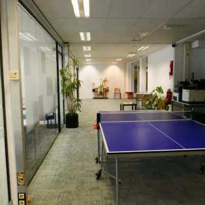 Spacious office at Wijnhaven 76, Rotterdam Center, featuring a casual meeting area with a ping pong table, plants, and seating. Ideal for office space rental.