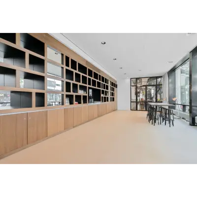 Spacious furnished office available for rent at Weena 290, Rotterdam Central Station, featuring modern interiors with wooden shelving and large windows offering natural light.