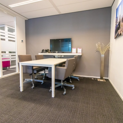 Furnished office space rental at Weena-Zuid 130, Rotterdam Central Station with meeting table, chairs, screen, and modern decor.