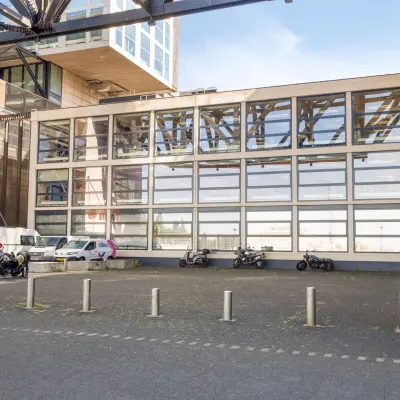 Exterior view of the office building at Lloydstraat 21 B, Rotterdam Delfshaven, featuring a modern facade and parking area. Ideal for office space rental opportunities.