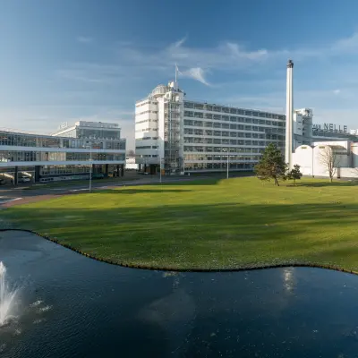 Exterior view of Van Nelleweg 1 in Rotterdam Delfshaven, an inviting location for office space rental, featuring a spacious landscape with a fountain.