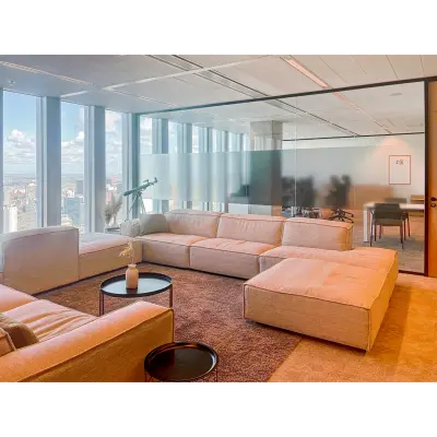 Spacious office lounge with comfortable seating and large windows offering a view of Rotterdam. Ideal for relaxing in a rented office space.