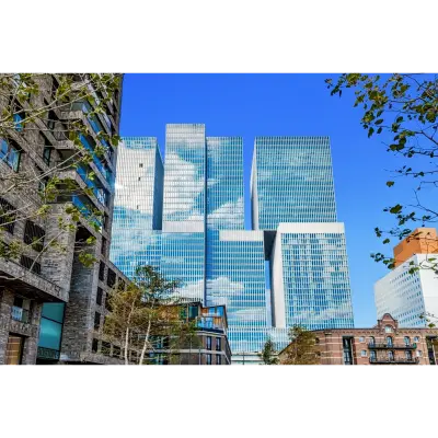Exterior view of a modern office building located at Wilhelminakade 173, Rotterdam Kop van Zuid, ideal for office space rental with glass facade reflecting the blue sky.