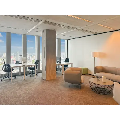 Bright office space at Wilhelminakade 173 in Rotterdam Kop van Zuid, featuring desks, chairs, and a comfortable seating area with a view of the city skyline.