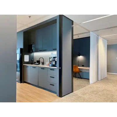 Modern office kitchen area with sleek cabinets and a coffee machine located in Rotterdam Kop van Zuid. Adjacent workspace for office space rental.