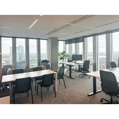 Modern office space at Wilhelminakade 173, Rotterdam Kop van Zuid, featuring large windows and multiple desks, ideal for workspaces. A perfect spot for office space rental with a panoramic city view.
