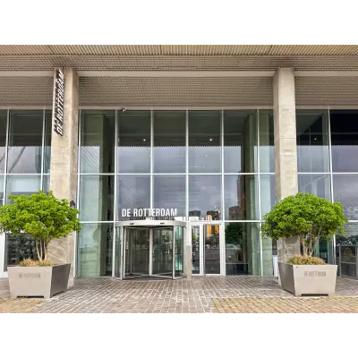 The modern entrance of an office building at Wilhelminakade 173, Rotterdam Kop van Zuid, showcasing a glass facade with large planters.