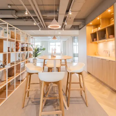 Modern office space at Wilhelminaplein 1-40, Rotterdam Kop van Zuid, featuring a stylish lounge area with wooden furnishings and an open layout for rent.