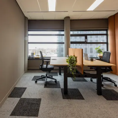 Bright office space at Wilhelminaplein 1-40 in Rotterdam Kop van Zuid, featuring two workstations by a large window, perfect for office space rental.